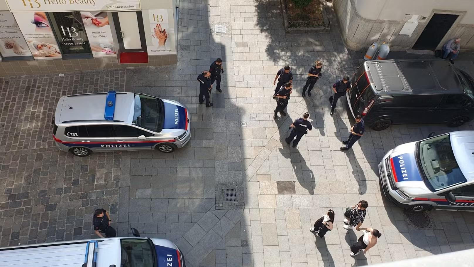 تجمع عدد من عناصر الشرطة في منطقة وسط المدينة بالقرب من متاجر تجميل، مع وجود سيارات الشرطة في الصورة.