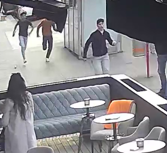 لقطة من مقهى تظهر أربعة أشخاص يركضون في اتجاه مختلف بينما توجد امرأة ترتدي ملابس بيضاء تتجه نحوهم.
