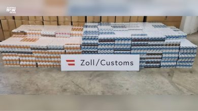 سجائر مهربة ضبطتها الجمارك النمساوية مكدسة أمام لافتة Zoll/Customs